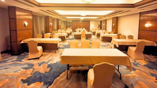 A spacious banquet hall at Pride Plaza Ahmedabad, featuring multiple tables set up for a conference or event.